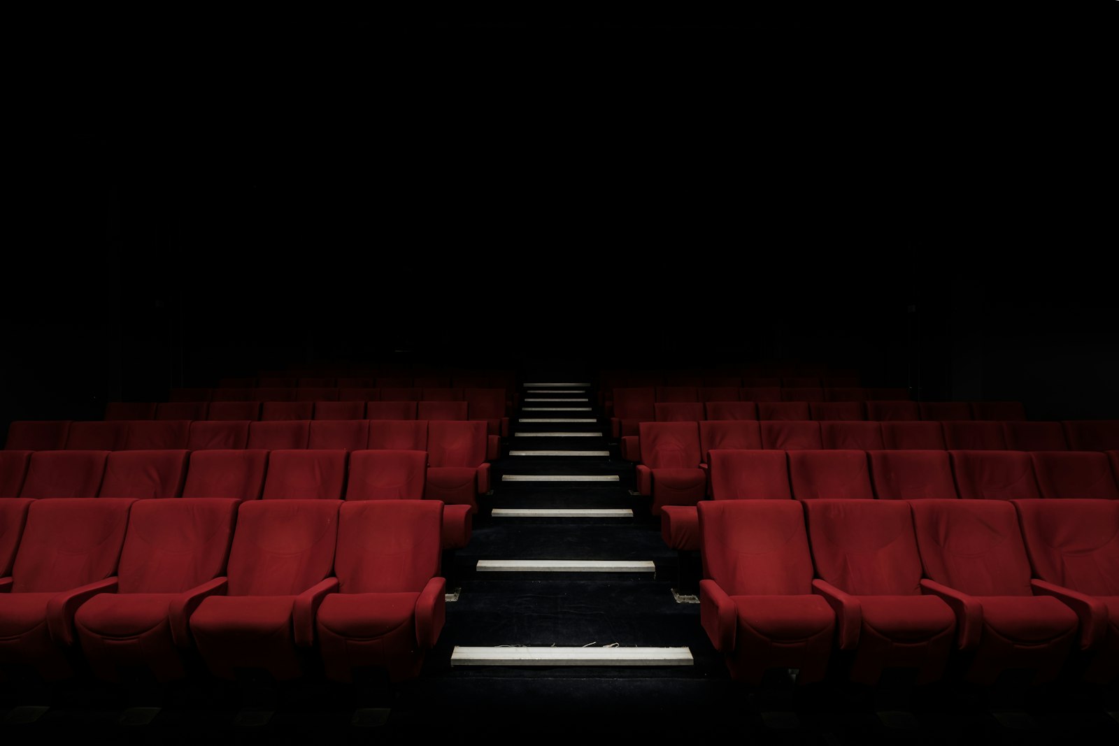 Butacas de cine vacías frente a una pantalla encendida